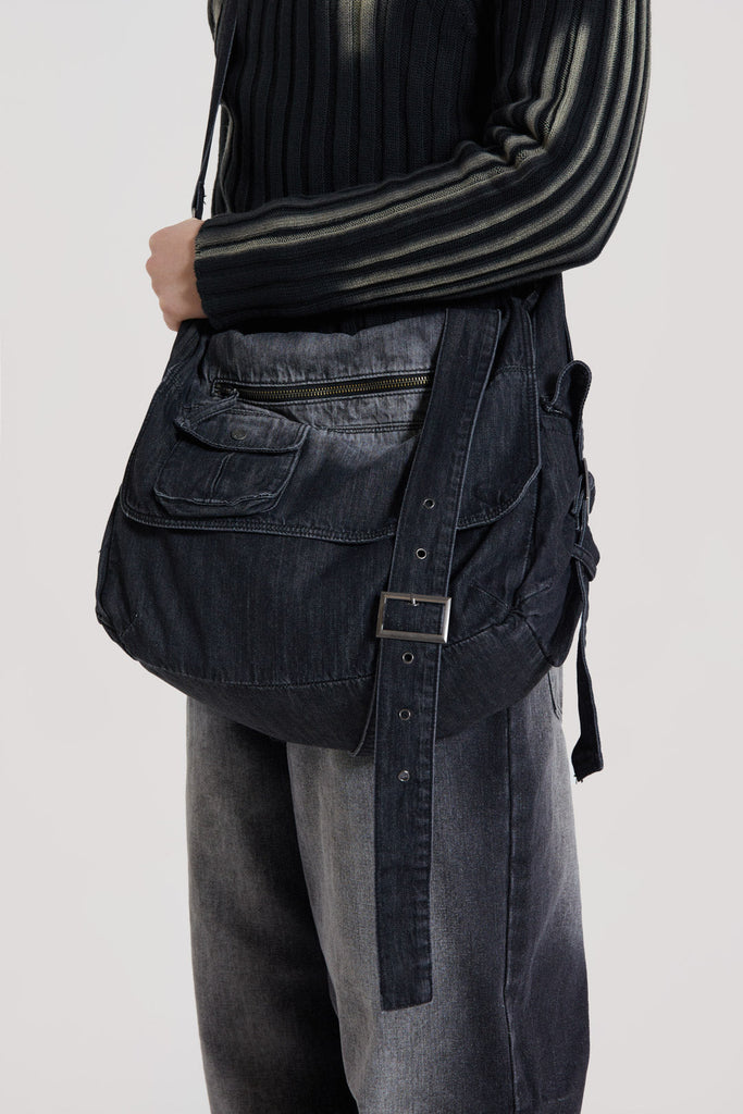 This washed black messenger bag is crafted in a washed black broken twill denim which features cargo pockets and an adjustable wrap around strap.