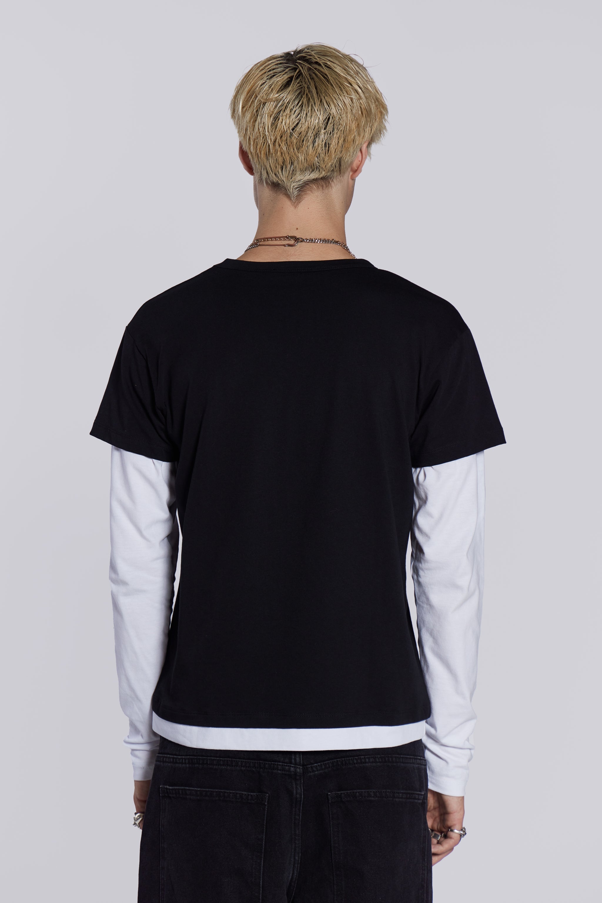 Man wearing graphic print double layer t-shirt, styled with black denim jeans/