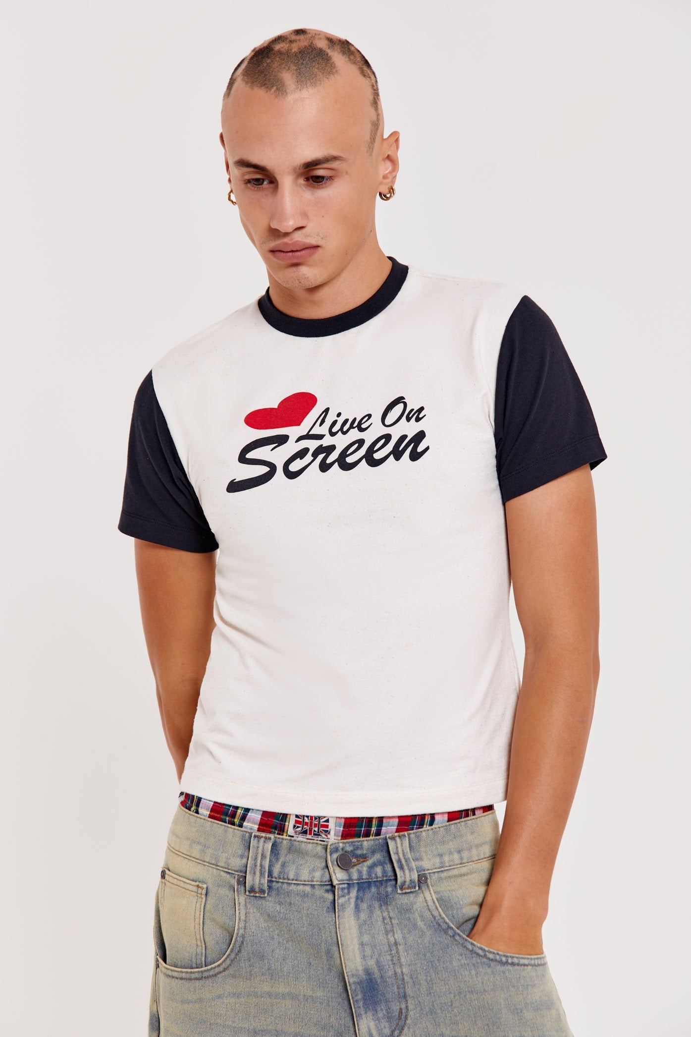 Male wearing white short sleeve crew neck t-shirt with Live On Screen print on front.