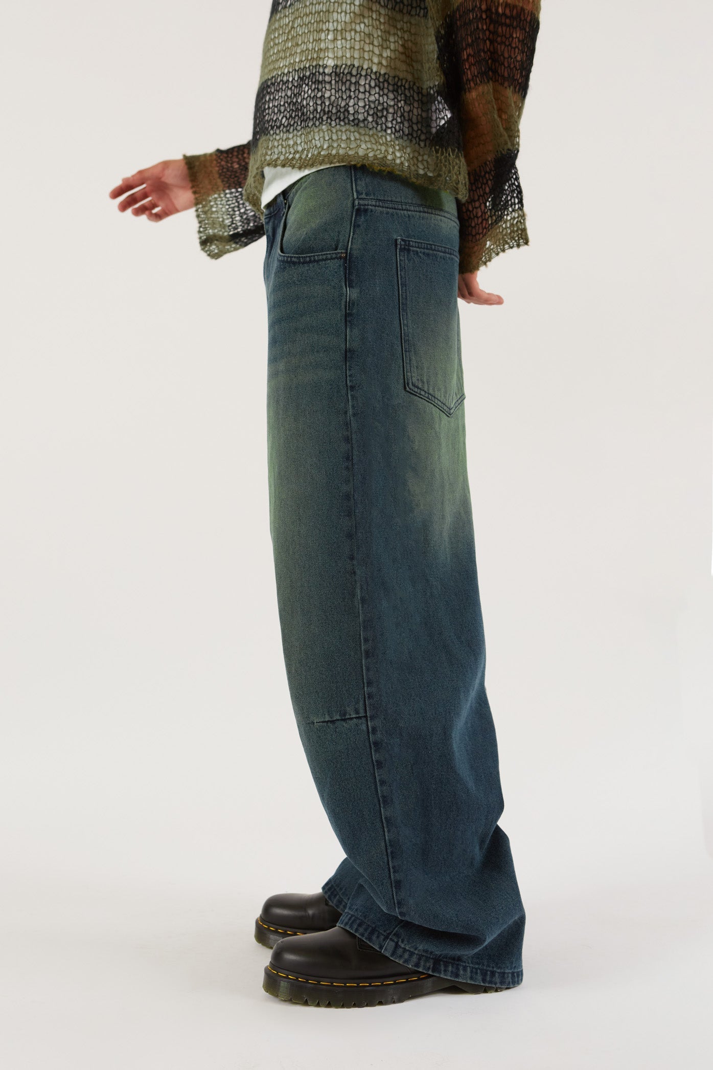 Male wearing Sandblast Oversized Skate Fit Denim Jeans. Styled with green and black knitted jumper. 