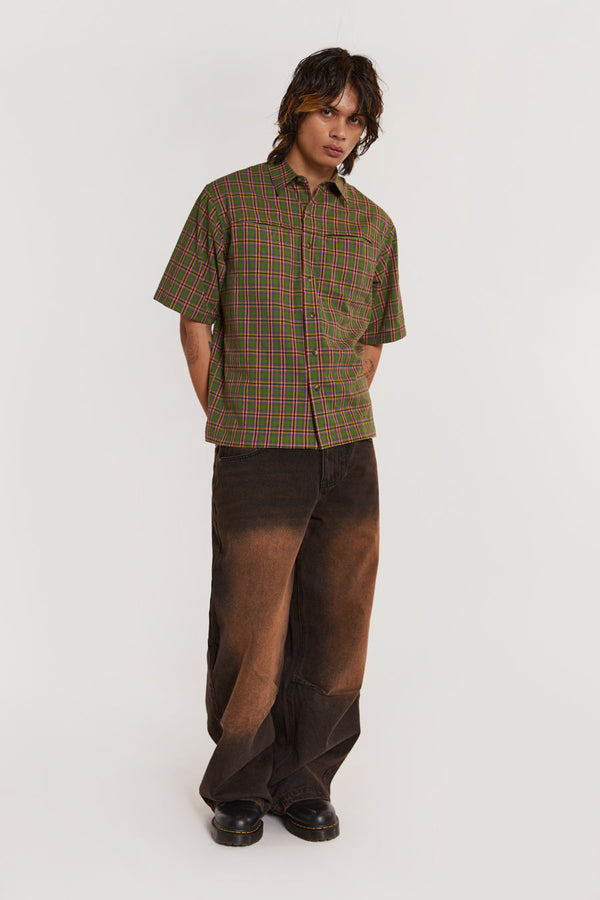 Male model wearing Green & pink Check Short Sleeve Shirt. Styled with brown colossus jeans.