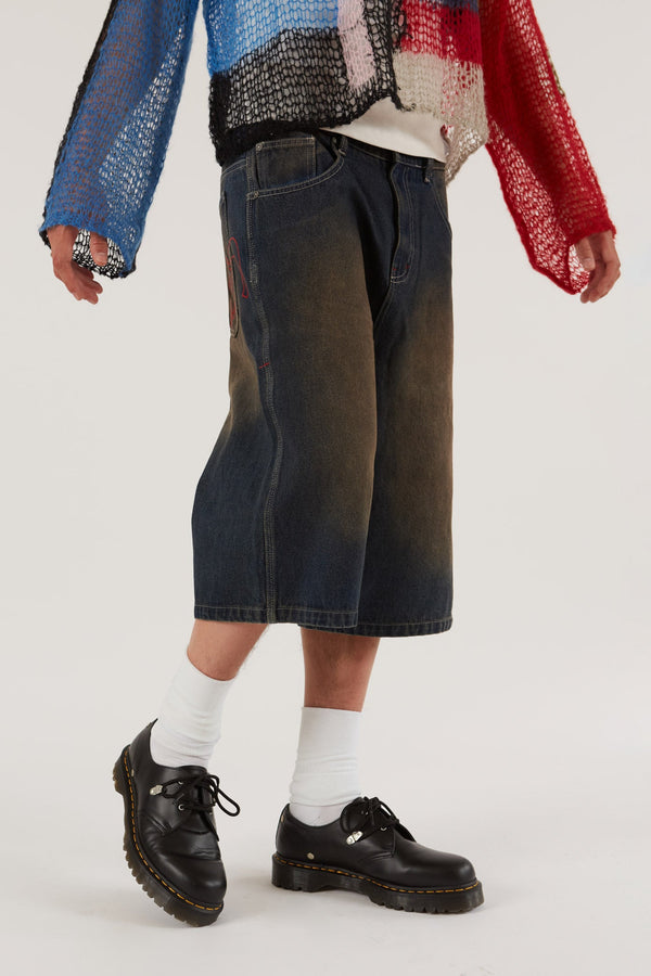 Male wearing Dark Rinse Denim Shorts Jumbo Fit. Styled with knitted jumper.