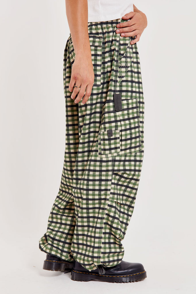 Male wearing green gingham printed check military style oversized cargo pants. 