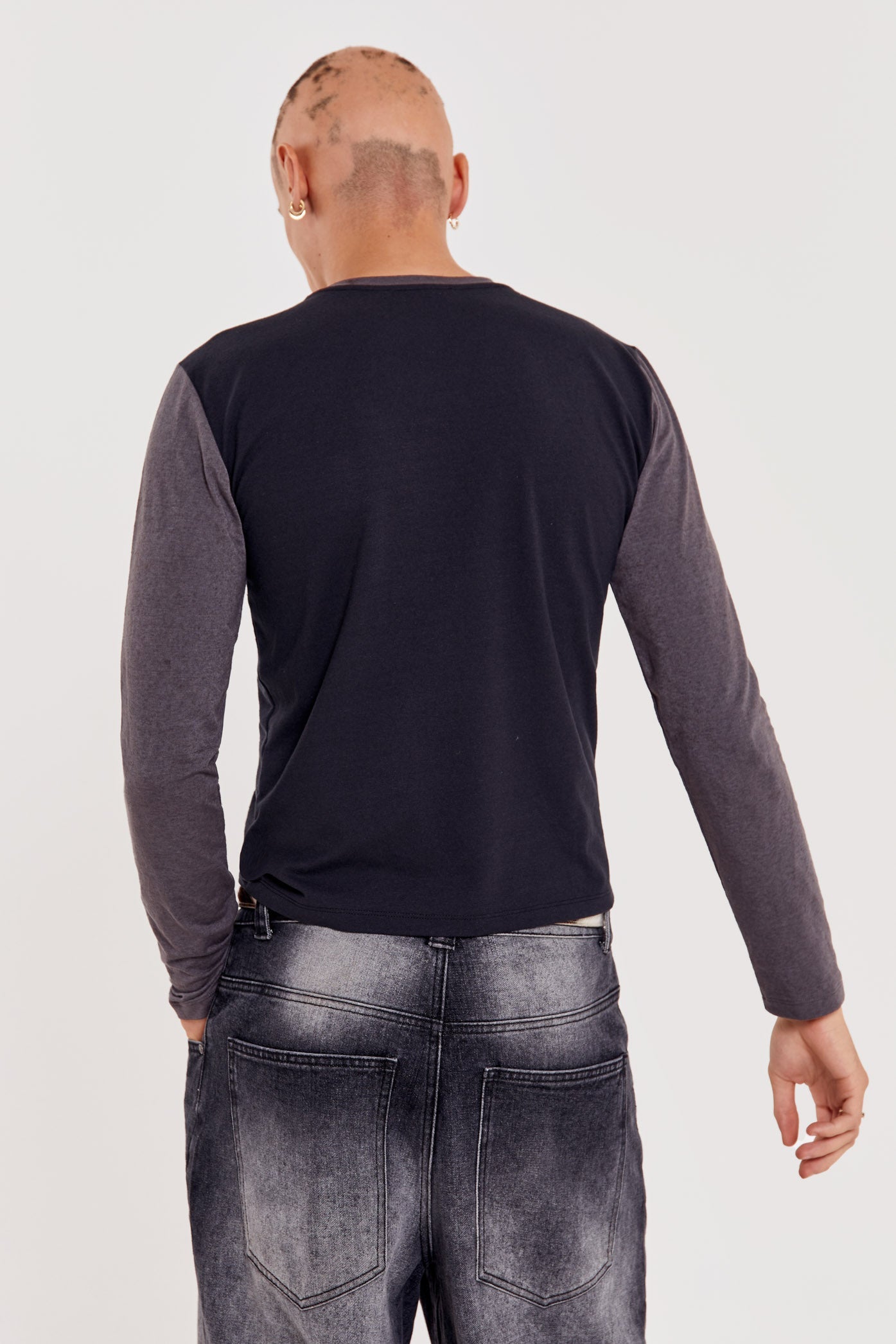 Male wearing black shrunken fit long sleeve tee with printed front. 