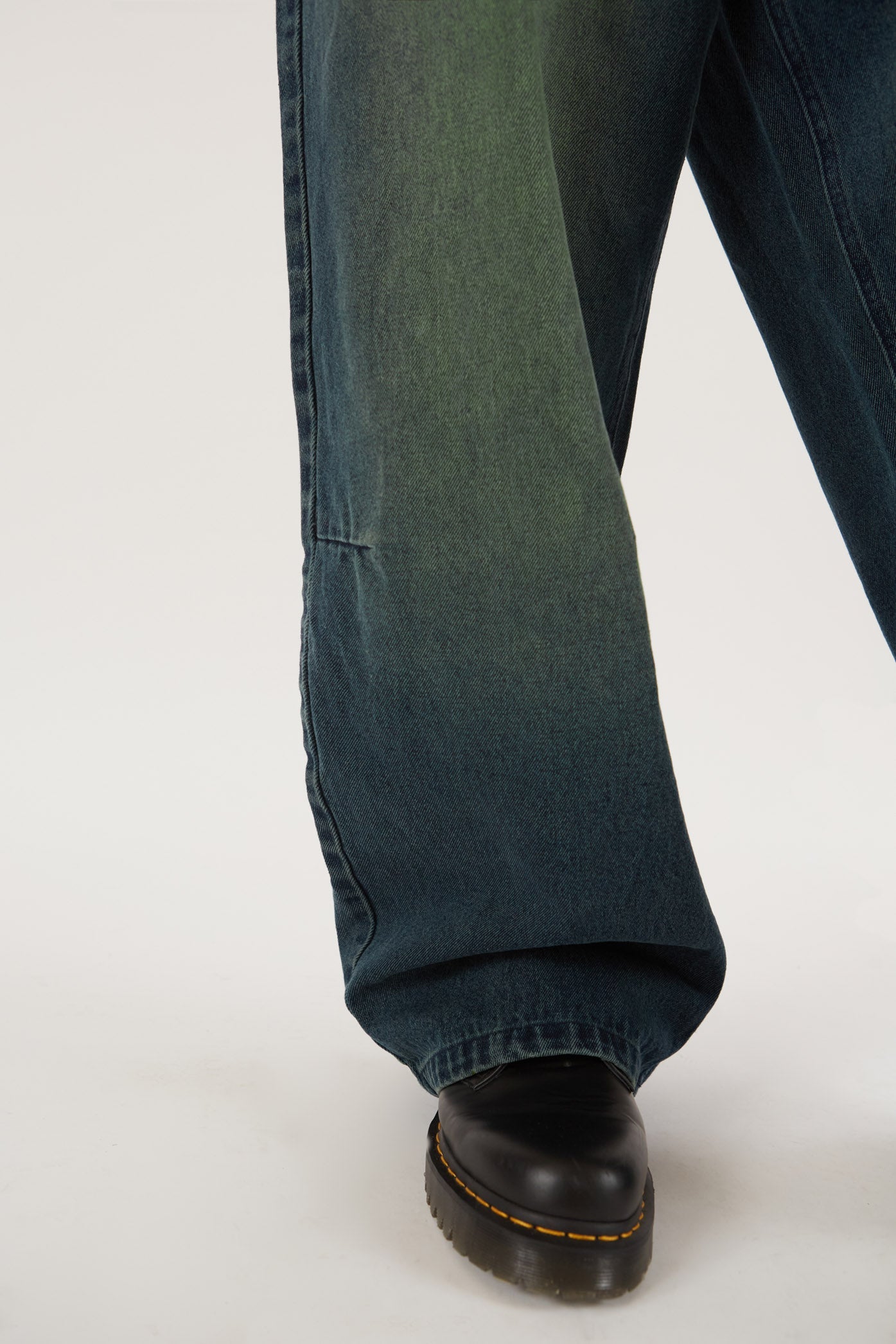 Male wearing Sandblast Oversized Skate Fit Denim Jeans. Styled with green and black knitted jumper. 