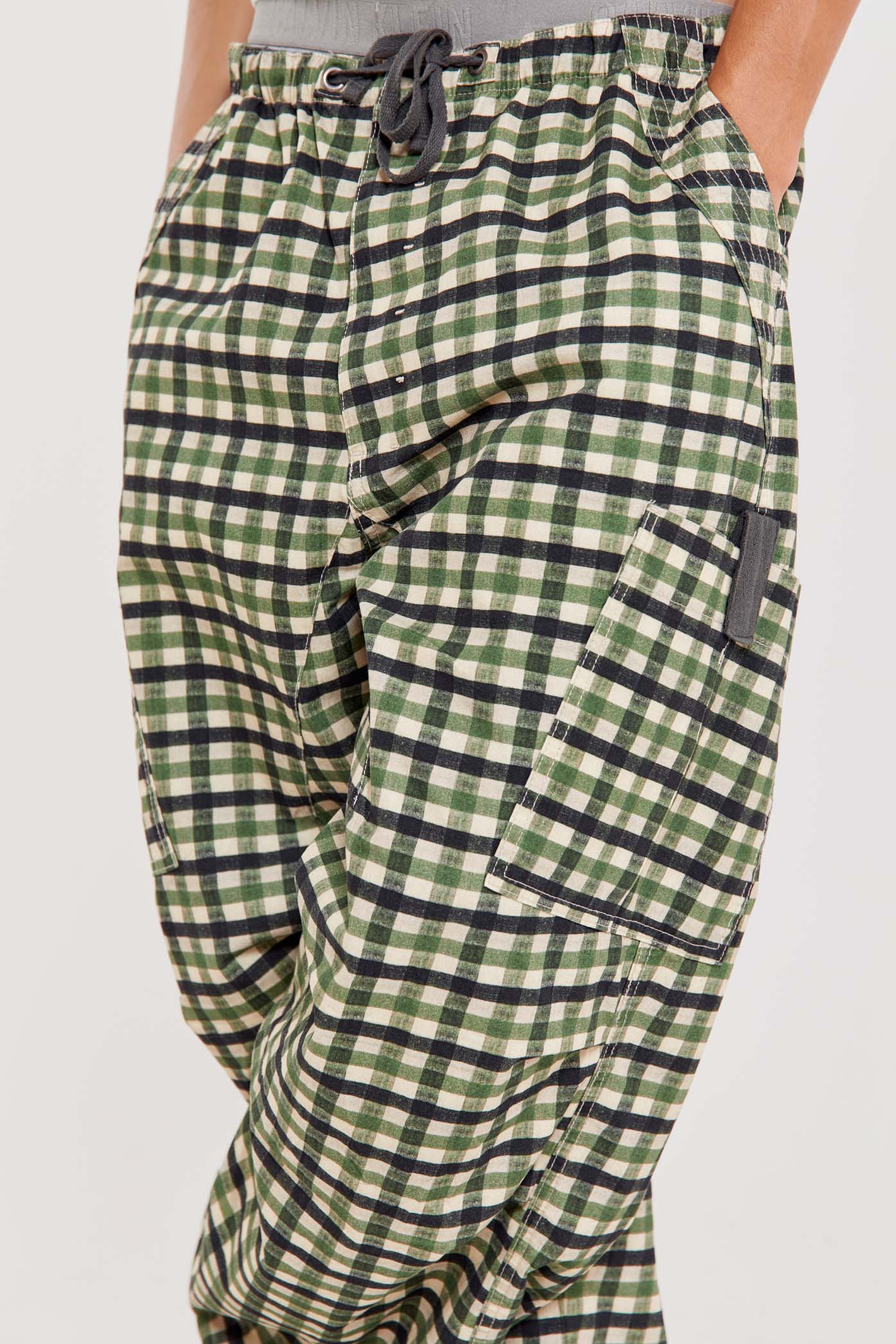 Male wearing green gingham printed check military style oversized cargo pants. 