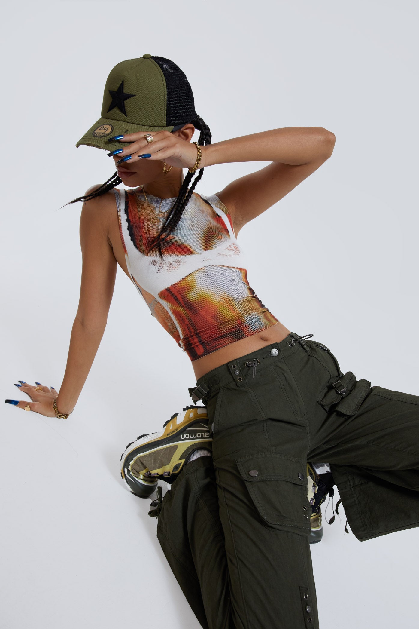 Female wearing khaki green slim fit low rise cargo trousers. Styled with bra illusion printed vest top. 