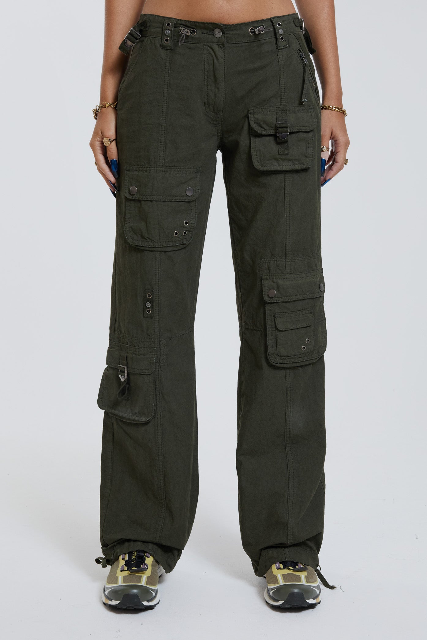 Female wearing khaki green slim fit low rise cargo trousers. Styled with bra illusion printed vest top. 