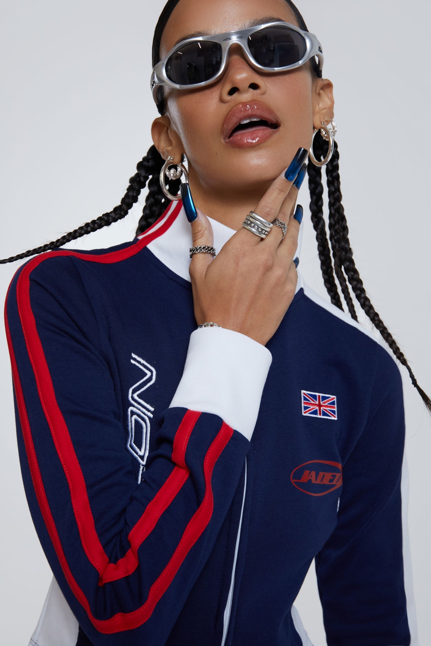 Female wearing navy high neck zip through slim fit long sleeve track top with Jaded branding detail. 