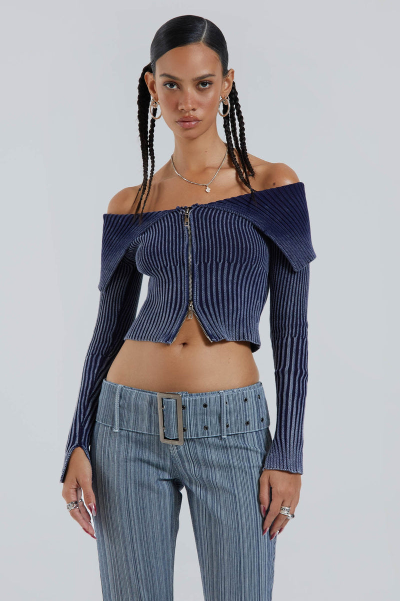 Female wearing blue denim look chunky wide rib knitted long sleeve off the shoulder top. 