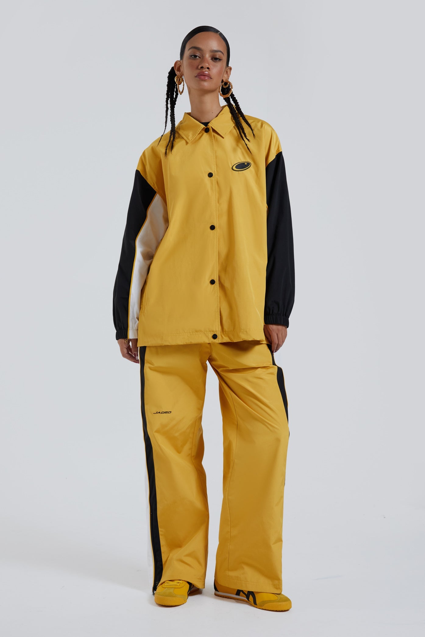 Female wearing yellow oversized track jacket with Jaded branding detail. Styled with the matching track pants. 