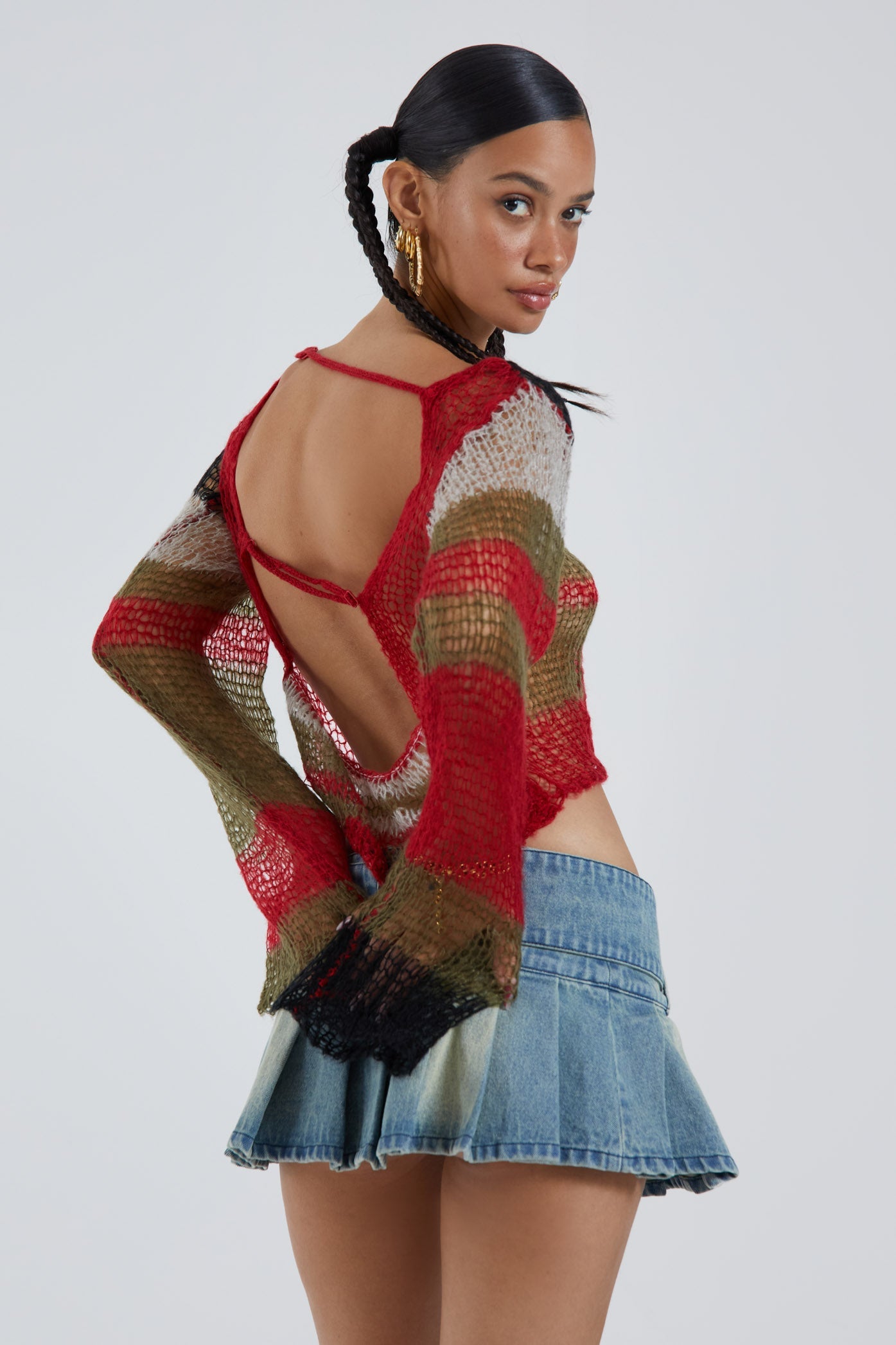 Female wearing multicoloured abstract fine knit long sleeve cropped jumper. Styled with the blue pleated denim mini skirt. 