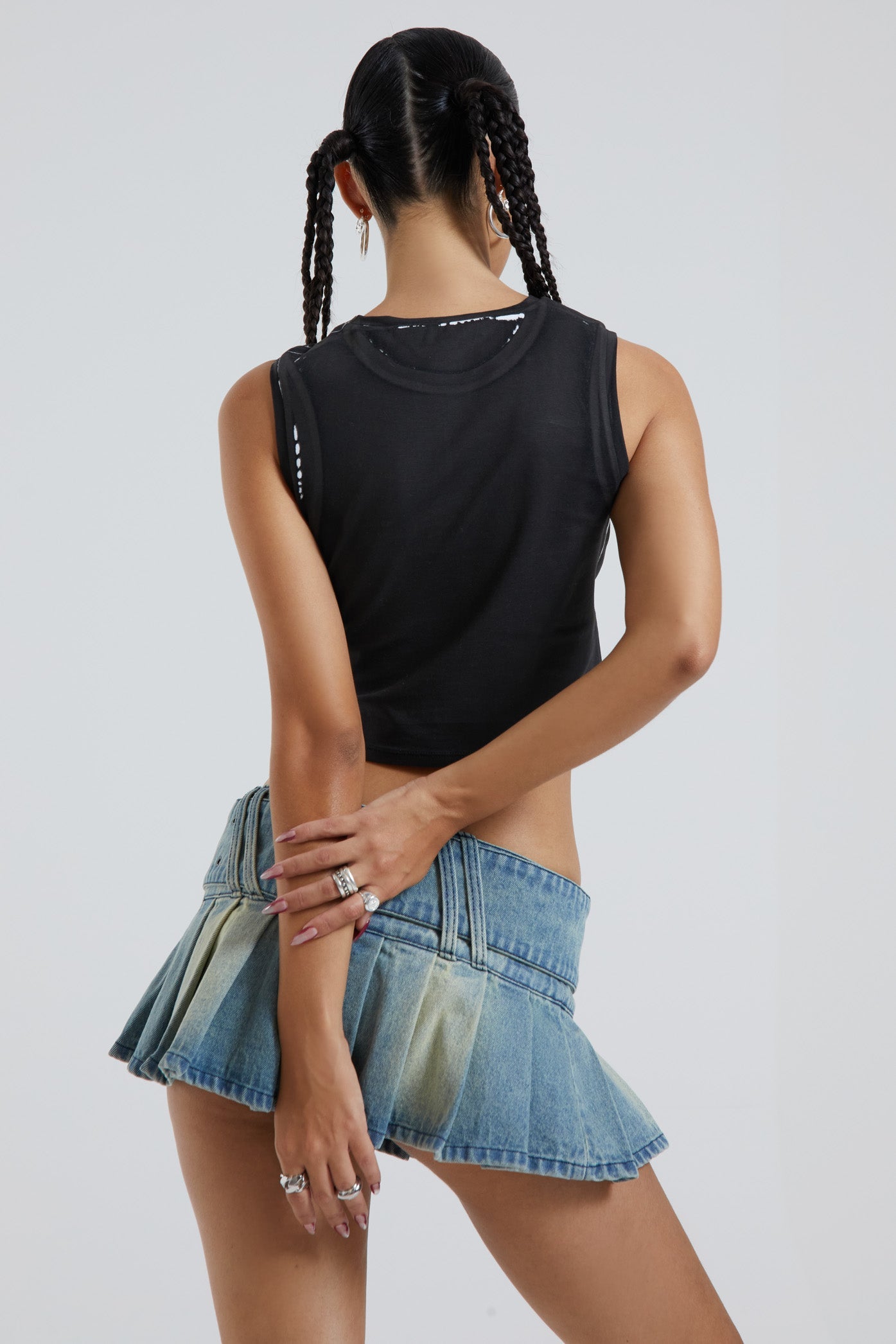 Female wearing motorcycle screen printed black crew neck sleeveless tank top. Styled with the blue denim pleated mini skirt. 