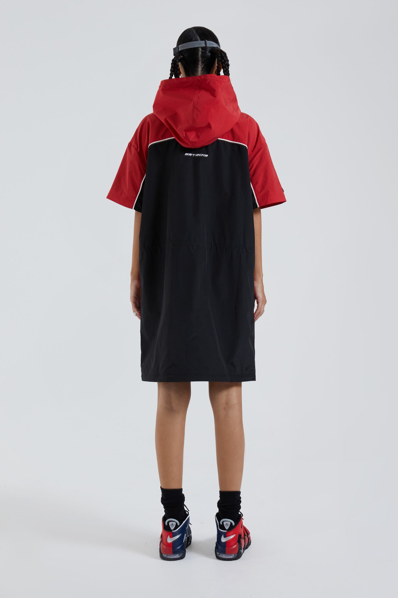 Female wearing red & black knee length short sleeve sporty cagoule coat. 