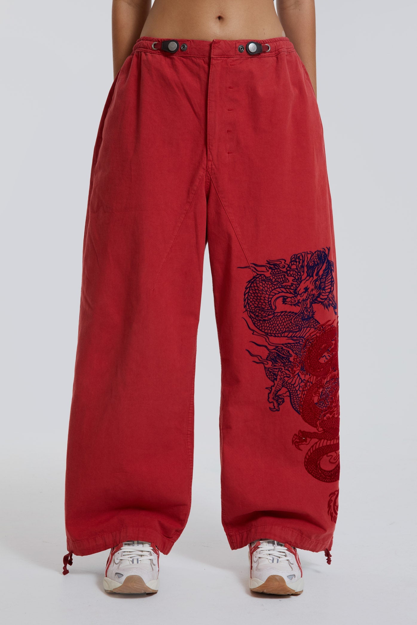 Female wearing red military cargo parachute pants with black dragon flock print. 