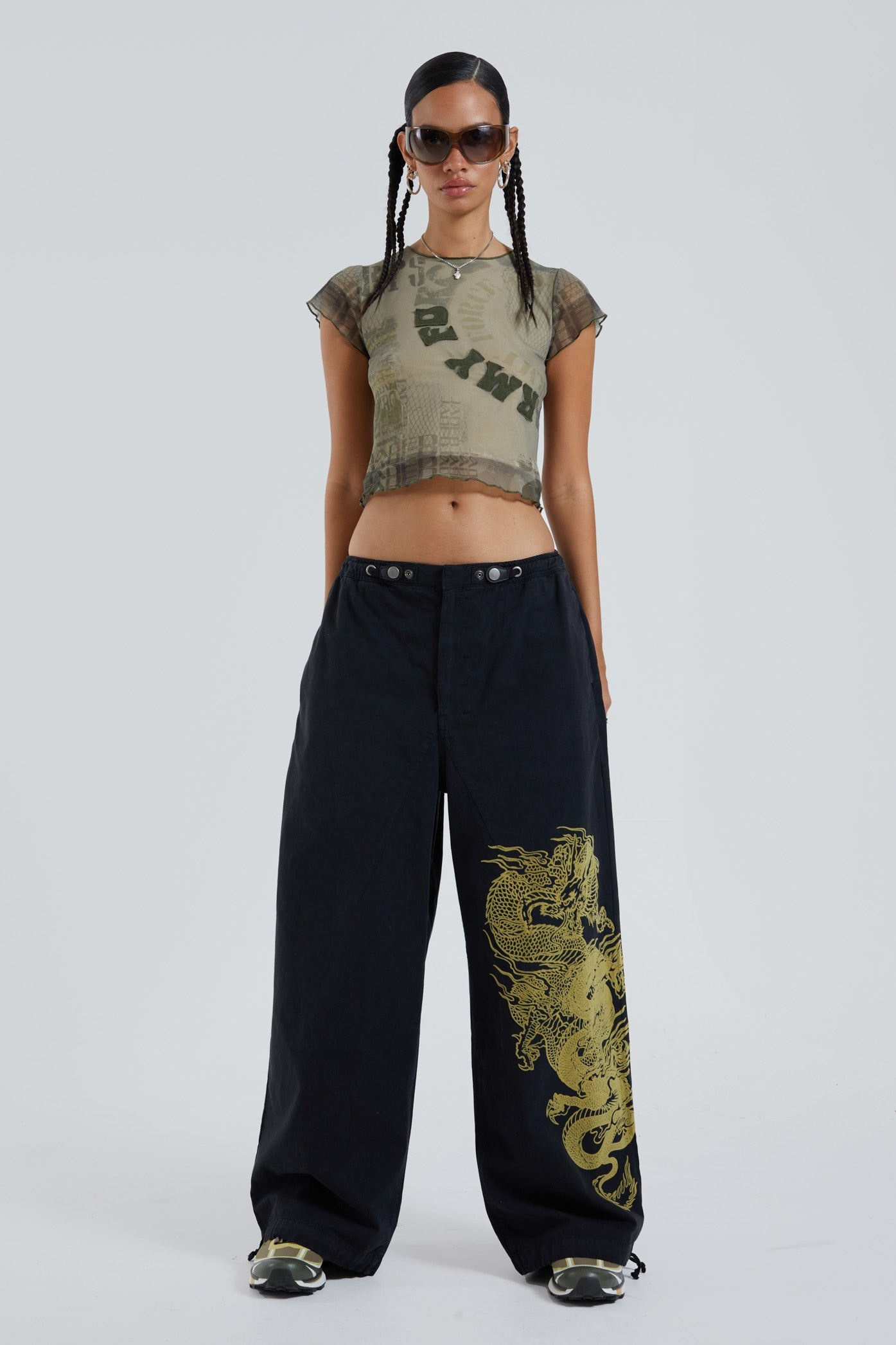 Female wearing black military cargo parachute pants with green dragon flock print. 