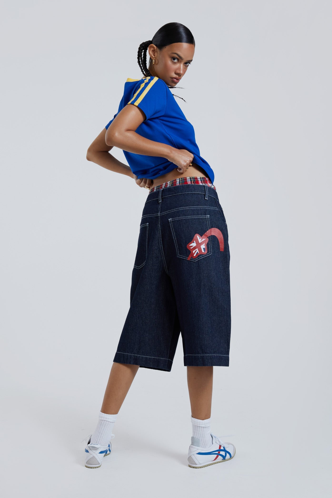 Female wearing sandblast washed denim oversized jorts in a jumbo fit with embroidered pocket patch detail. 