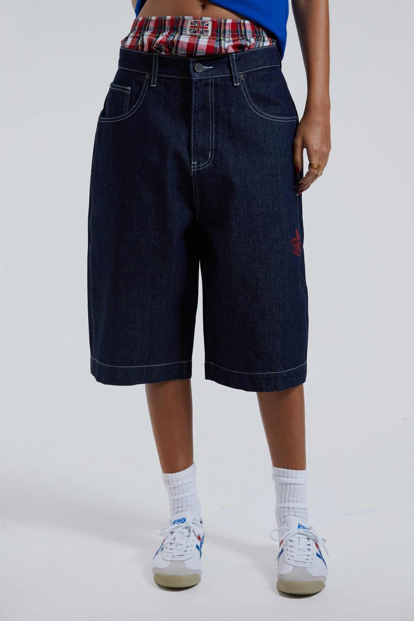 Female wearing sandblast washed denim oversized jorts in a jumbo fit with embroidered pocket patch detail. 