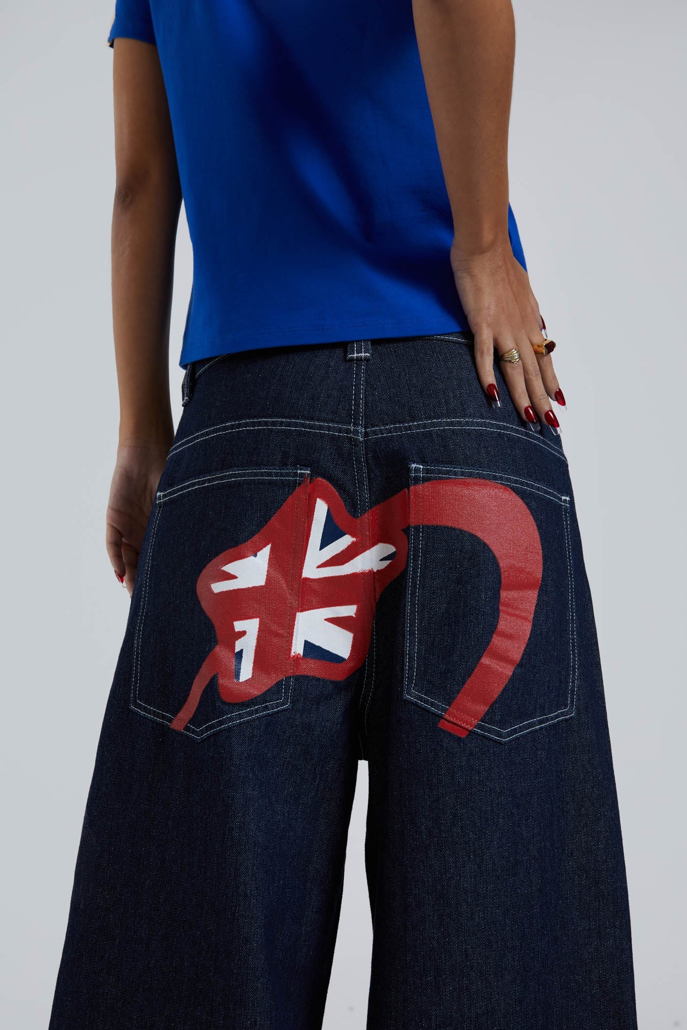 Female wearing sandblast washed denim jeans in an oversized skate fit with embroidered coin pocket and Union Jack artwork across back body and pockets. 