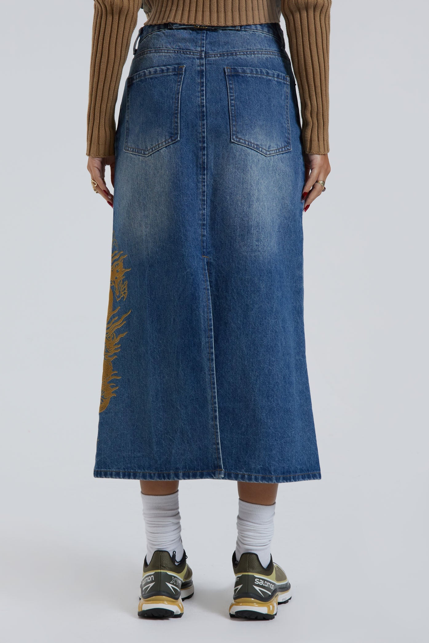 Female wearing sandblast washed denim 00's style maxi skirt with dragon flock print. 