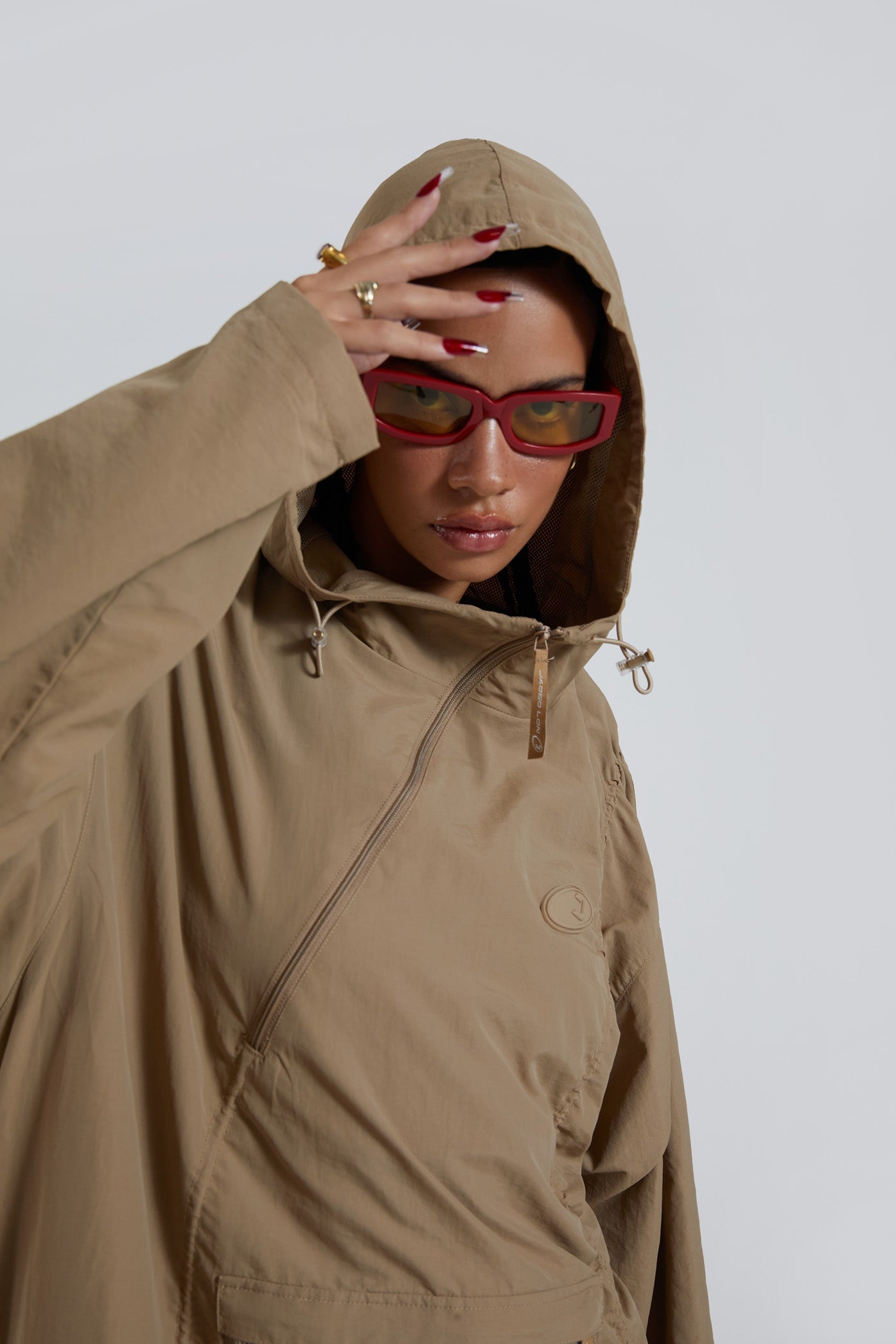 Female wearing stone khaki adjustable ruched detail maxi length long sleeve nylon jacket. 