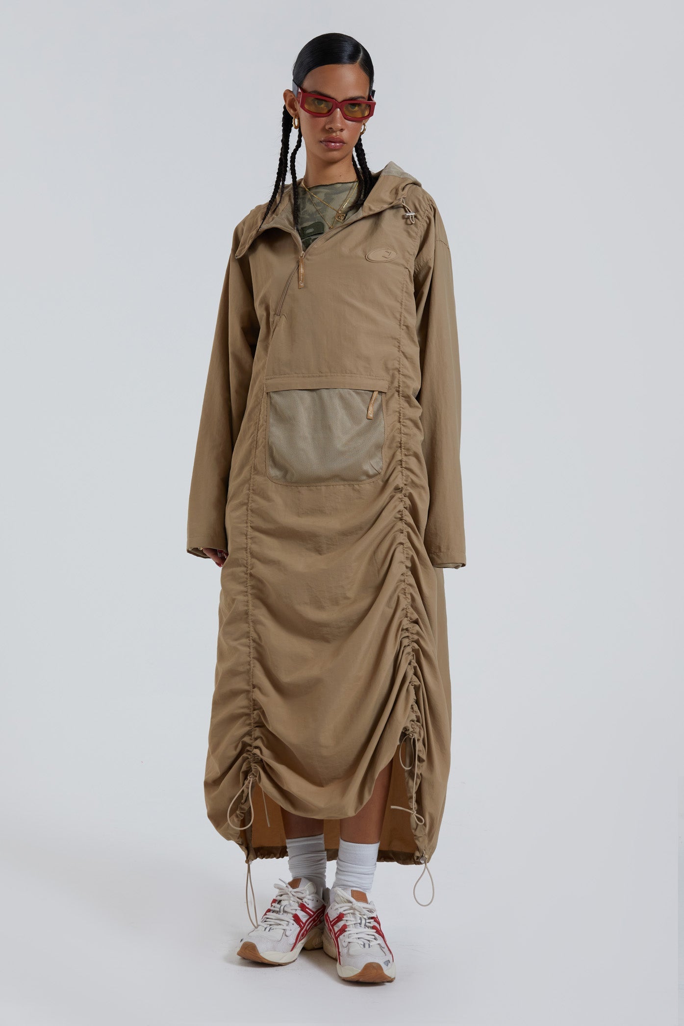 Female wearing stone khaki adjustable ruched detail maxi length long sleeve nylon jacket. 