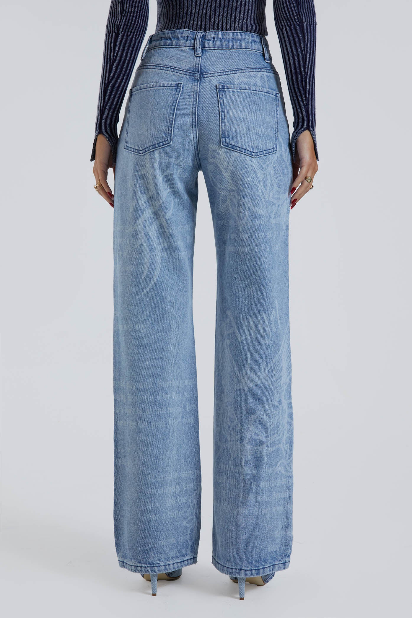 Female wearing Jaded Graffiti Discharge Print Slouchy Fit Boyfriend Jeans. Styled with blue ribbed knitted top.