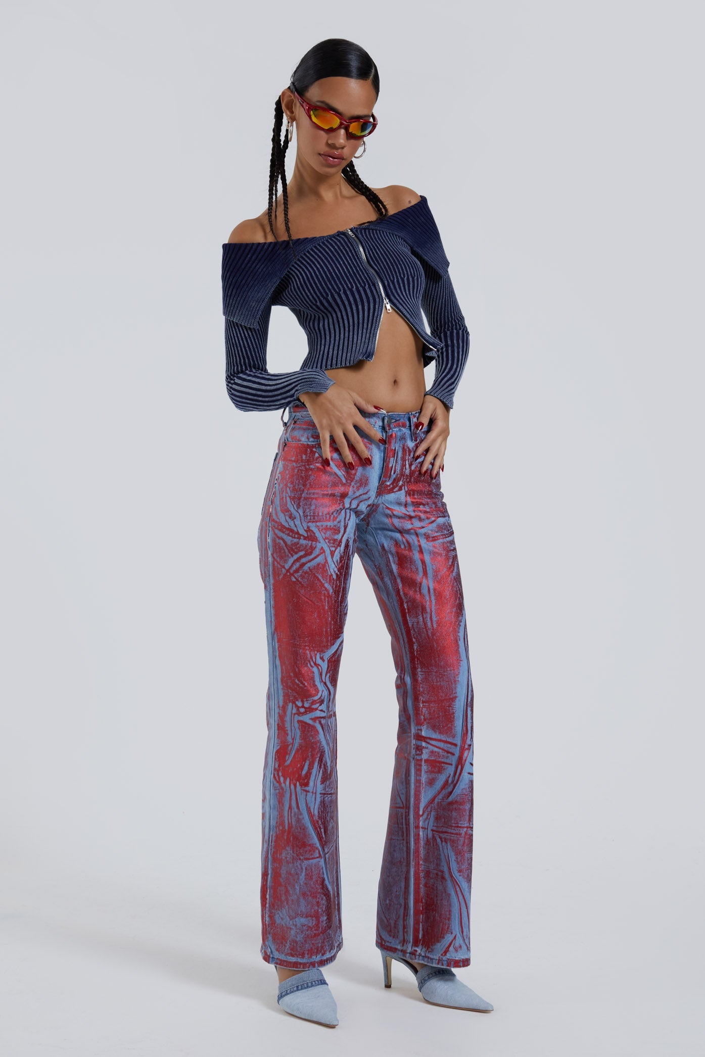 Female wearing blue and red distressed foil low rise fit 00’s style jeans. Styled with long sleeve blue knitted cardigan. 