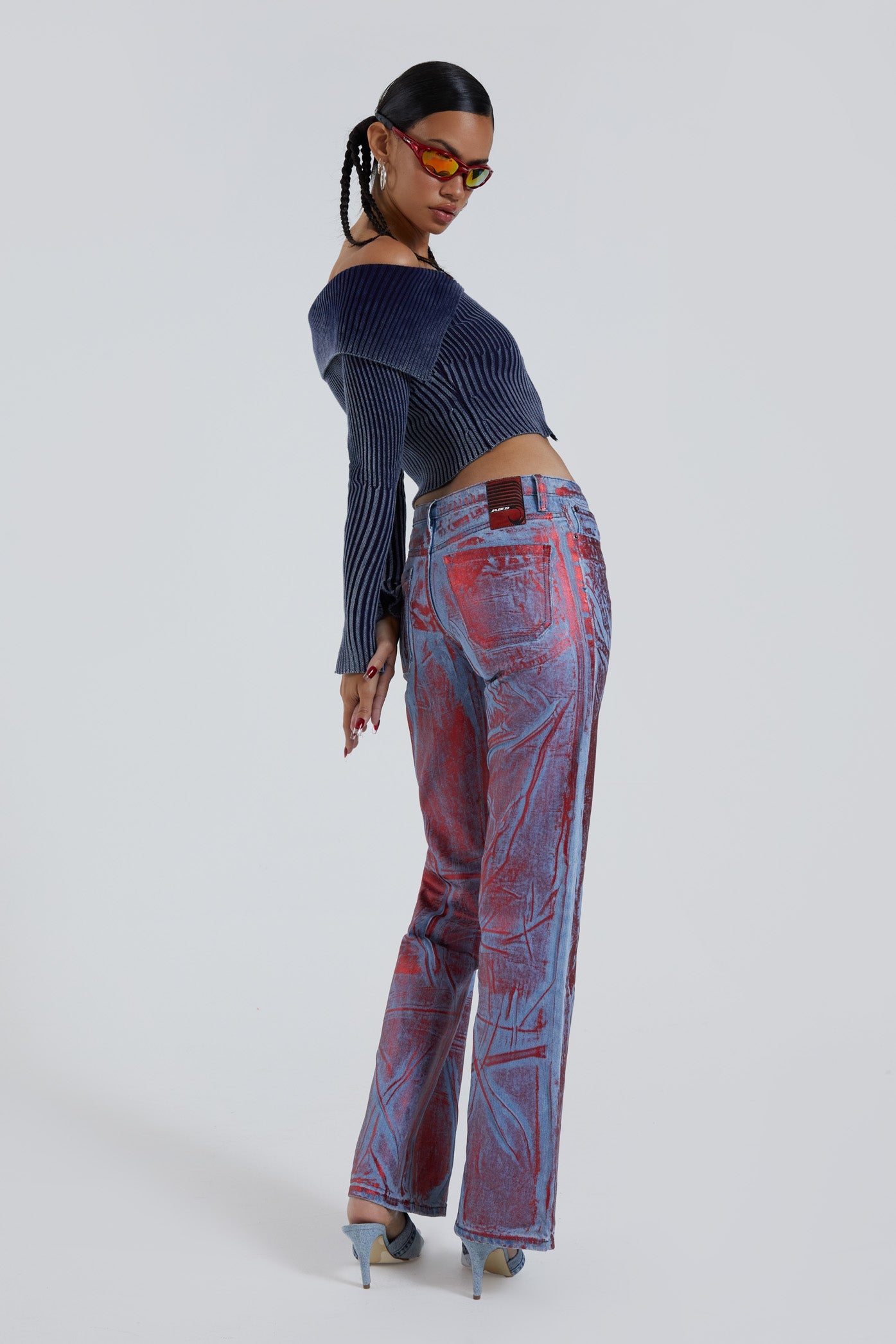 Female wearing blue and red distressed foil low rise fit 00’s style jeans. Styled with long sleeve blue knitted cardigan. 