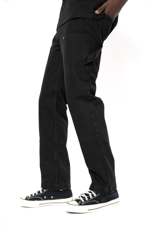 Close up shot of black carpenter trousers styled with a black t-shirt and black and white trainers.