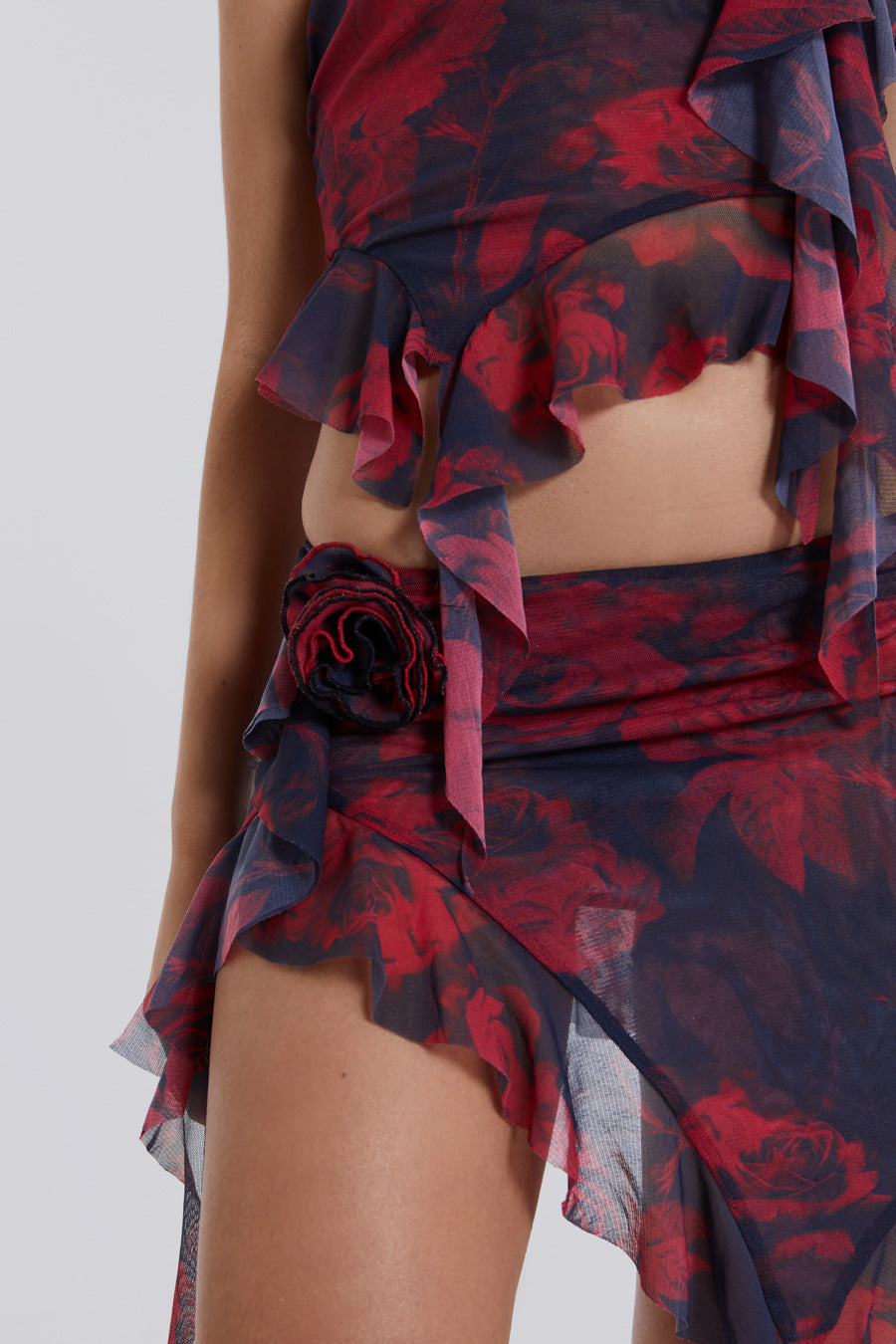 Female model wearing Dark Rose Print Asymmetric Bandeau Top. Styled with the matching asymmetric mini skirt and neck tie. 