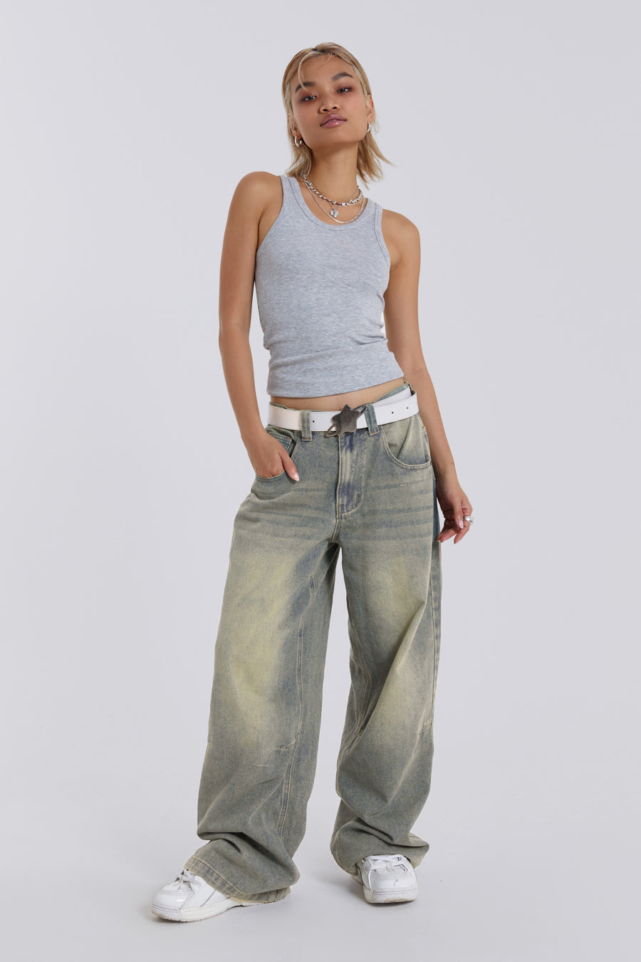 Female model wearing light was colossus fit jeans, styled with a grey top. 