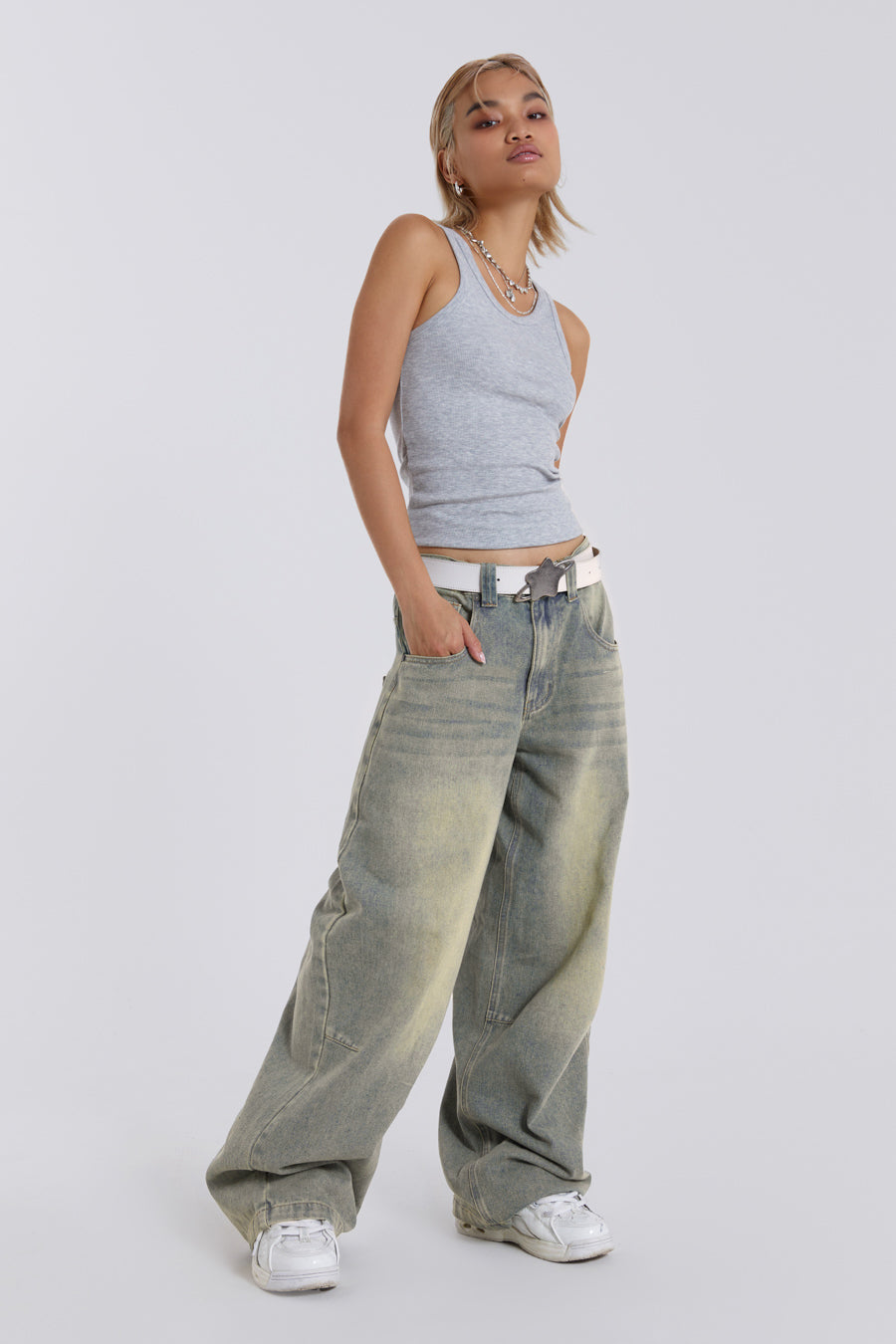 Female model wearing light was colossus fit jeans, styled with a grey top. 