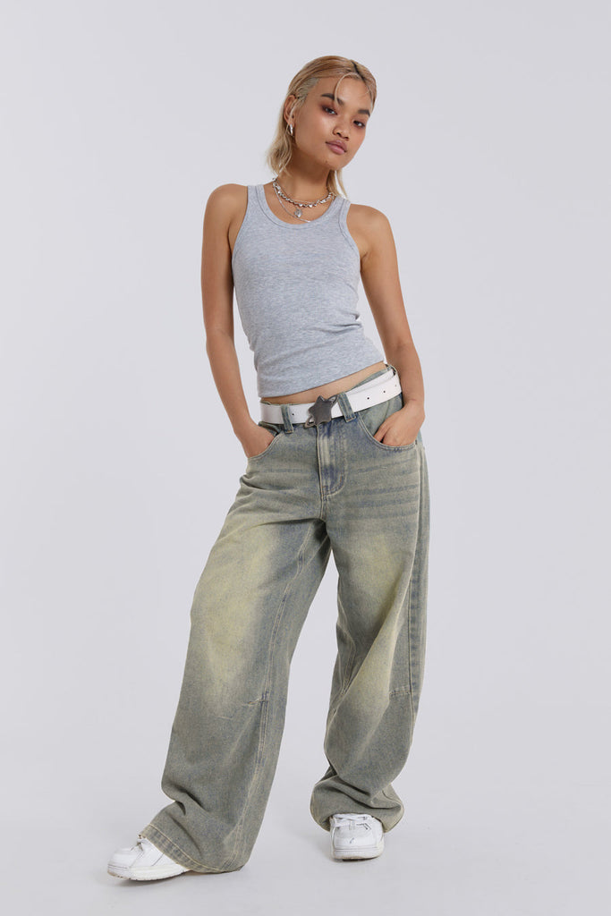 Female model wearing light was colossus fit jeans, styled with a grey top. 