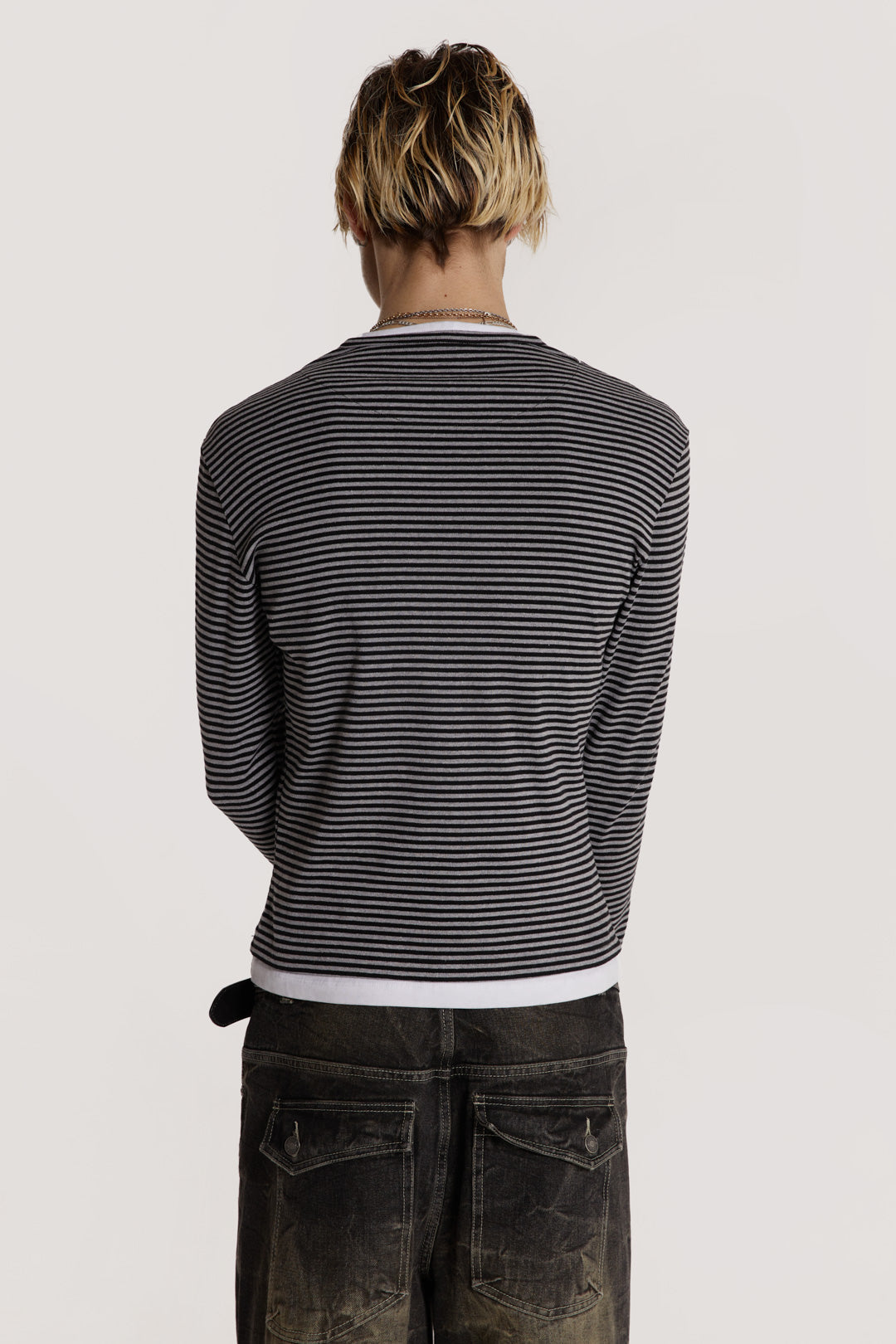 Male model wearing a grey tonal long sleeved striped jersey top designed with a lace up front and tonal screen print on the chest.