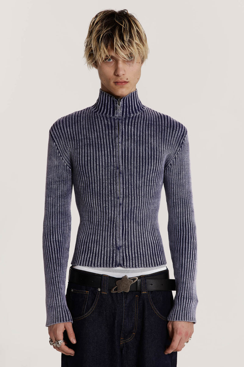 Male model wearing a blue track top crafted in a heavyweight knit with a funnel neck detail. The acid wash fabric gives the look of a washed denim material.