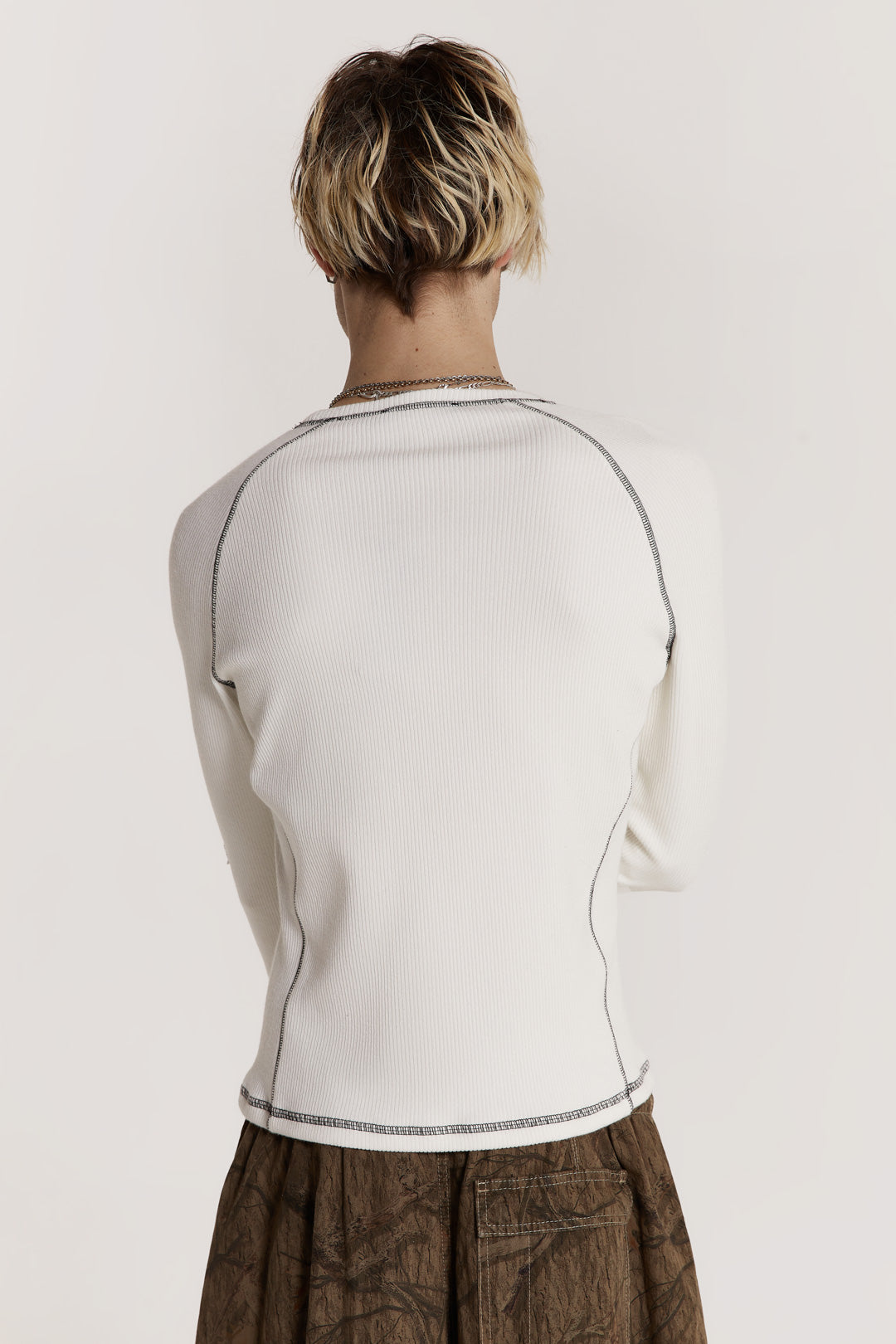 Male model wearing an off white shrunken fit long sleeve top curated in a heavy rib fabric with an applique raw edge star detail.