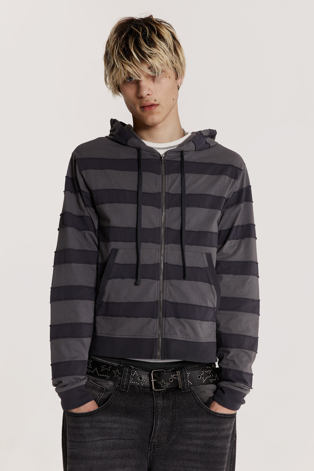 Male model wearing a grey tonal applique stripe jersey hoodie features a kangaroo patch pocket in a shrunken fit. 