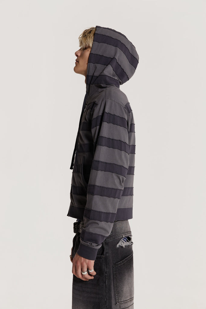 Male model wearing a grey tonal applique stripe jersey hoodie features a kangaroo patch pocket in a shrunken fit. 