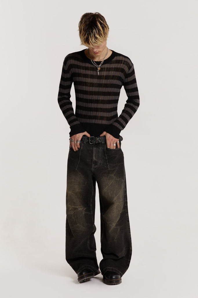 Male model wearing a black and grey striped jumper in a shrunken fit. 