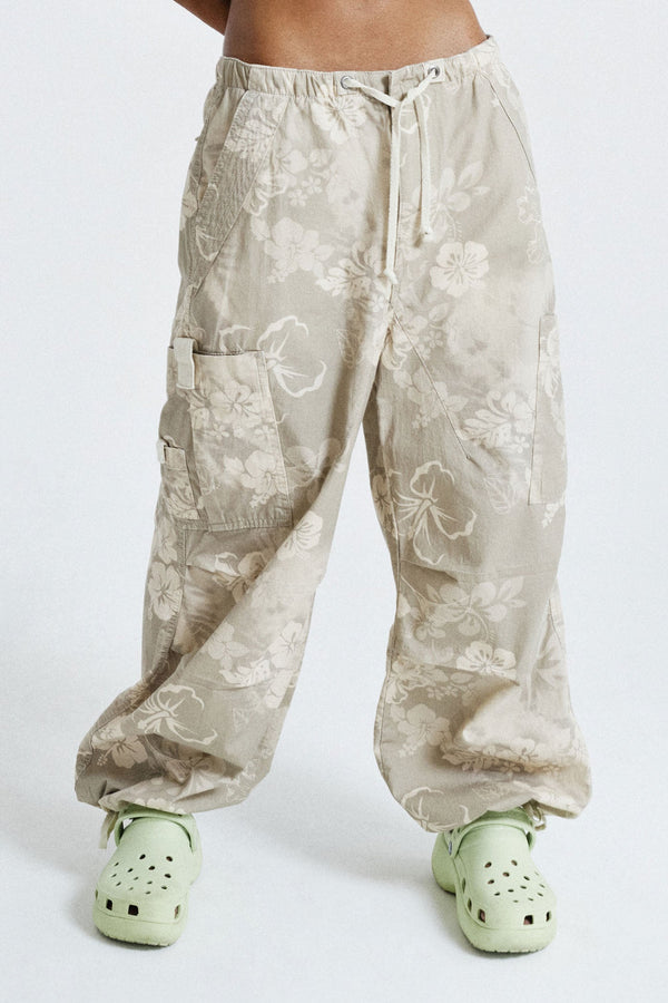 Female wearing Tonal Hawaiian Print Parachute Cargo Pants. Styled with white printed crop top.