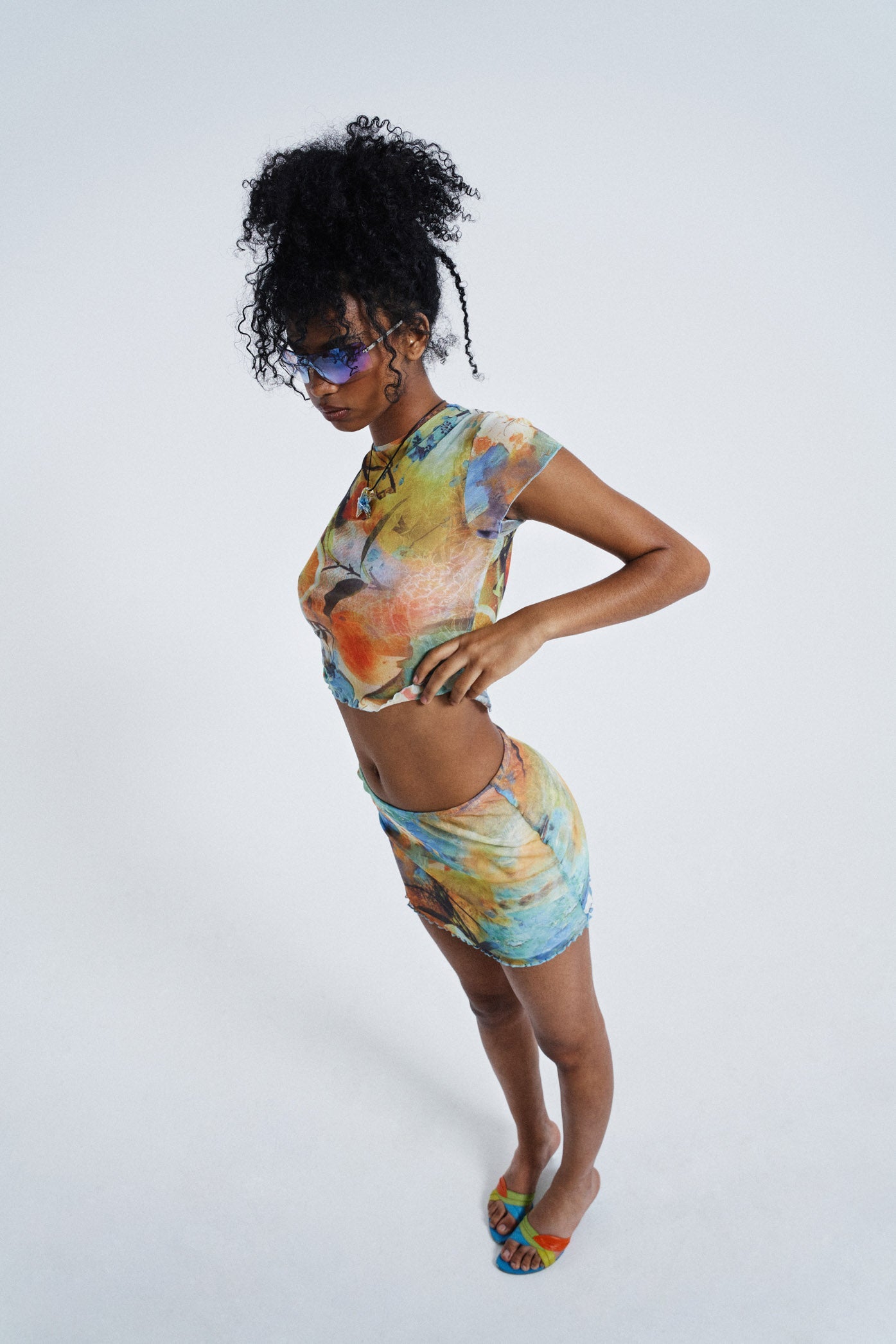 Female wearing Temple Orange Print Double Layer Vintage Mesh Mini Skirt. Styled with the matching crew neck crop top.