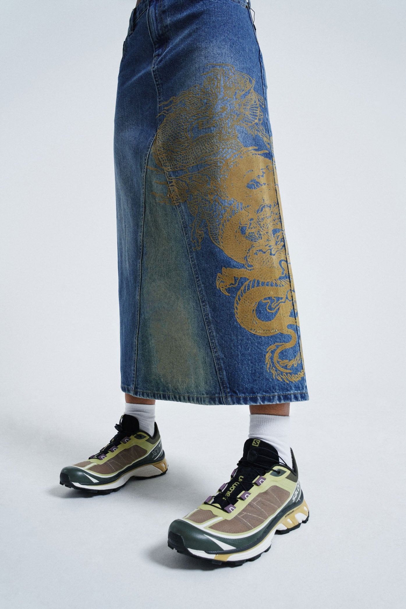 Female wearing sandblast washed denim 00's style maxi skirt with dragon flock print. 