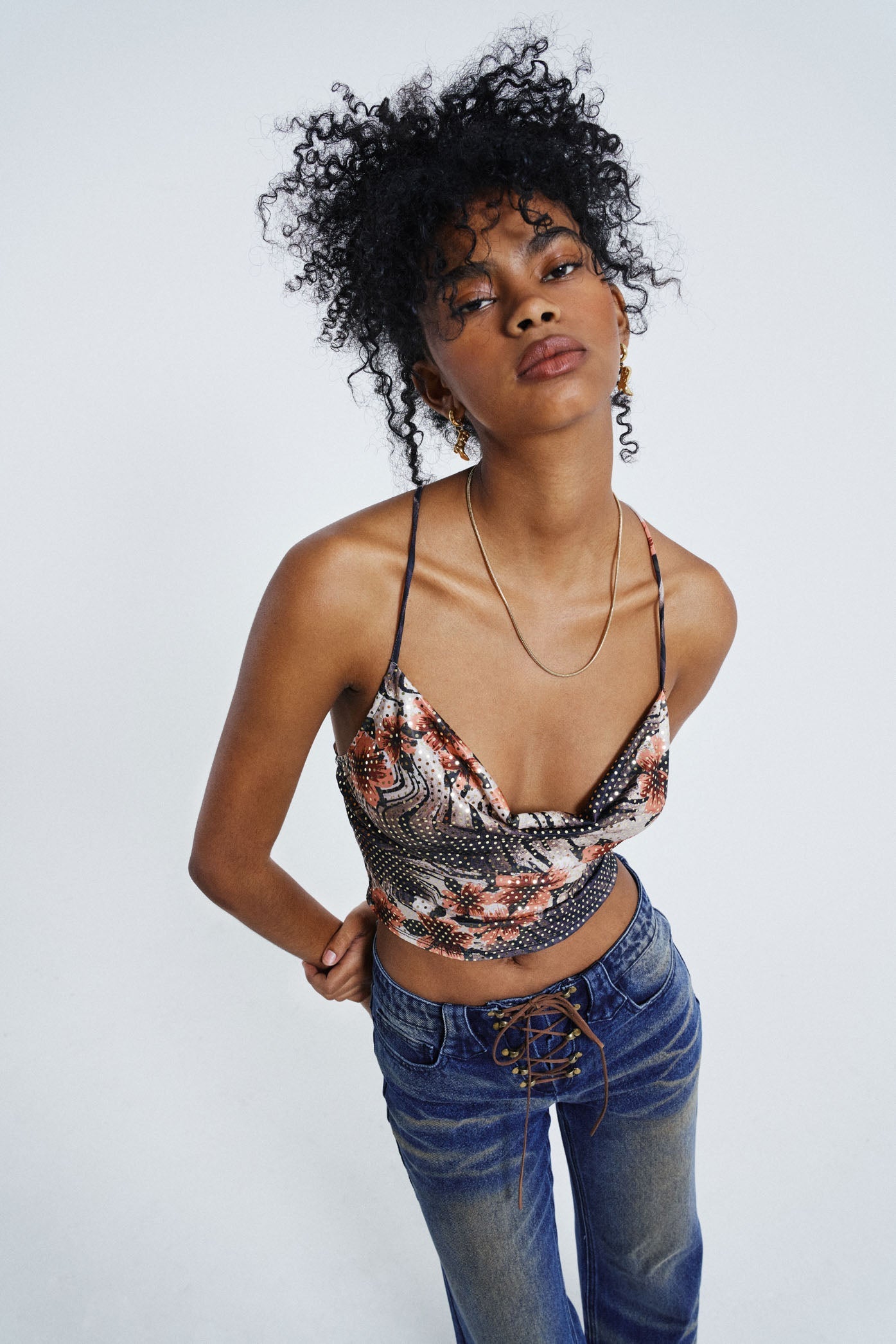 Female wearing Floral Print Cowl Neck Cami Top. Styled with washed blue lace up jeans.