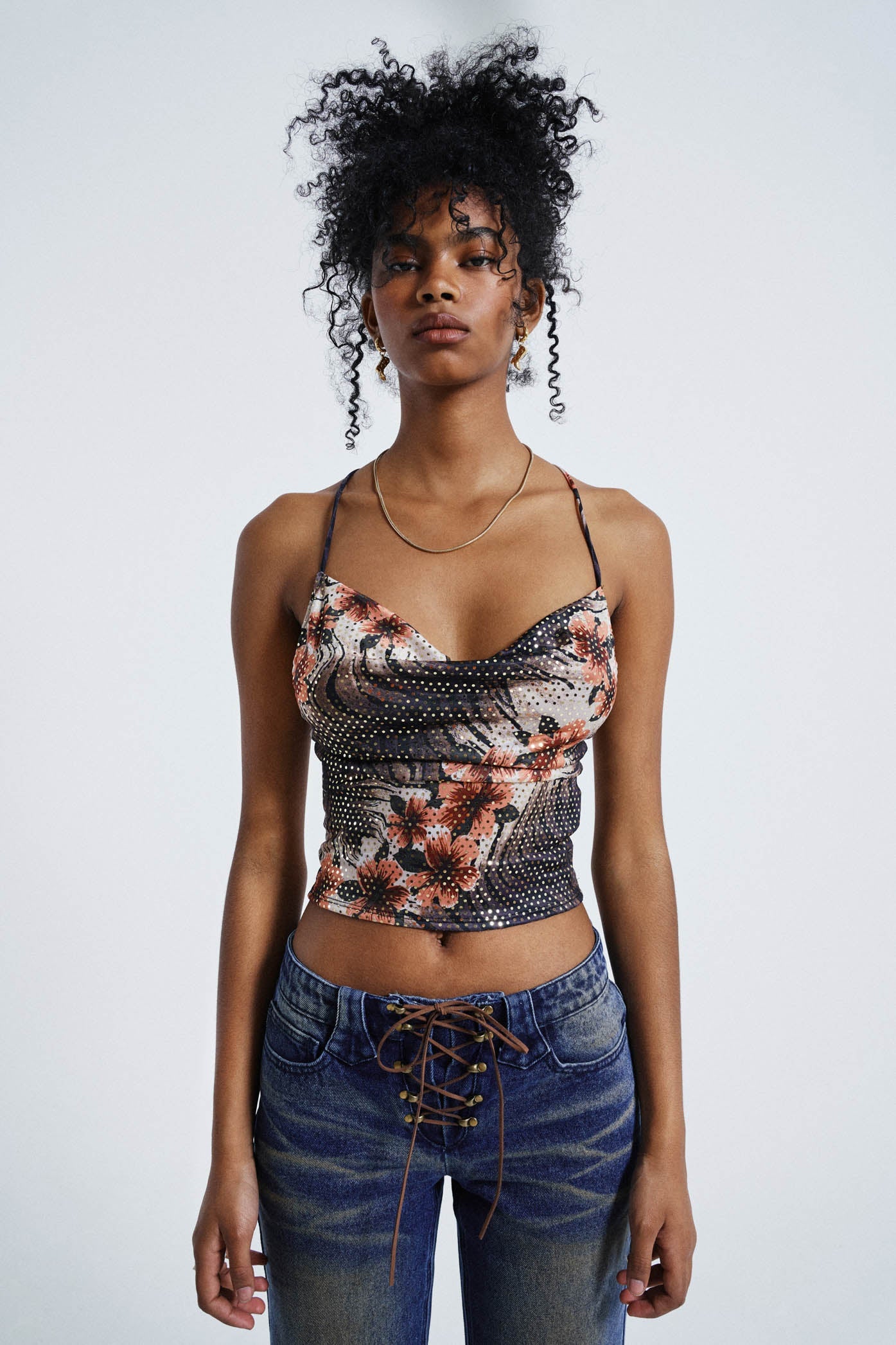 Female wearing Floral Print Cowl Neck Cami Top. Styled with washed blue lace up jeans.