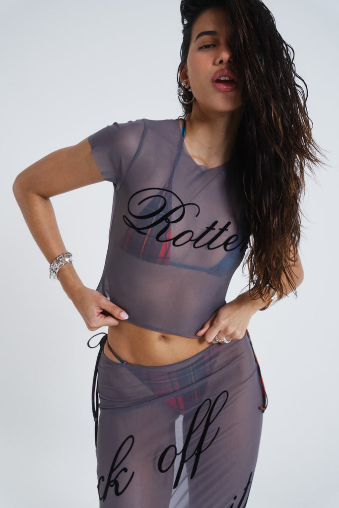 Female model wearing grey lightweight mesh t-shirt features a “rotten” black flock placement print. Paired with the matching mesh maxi skirt. 