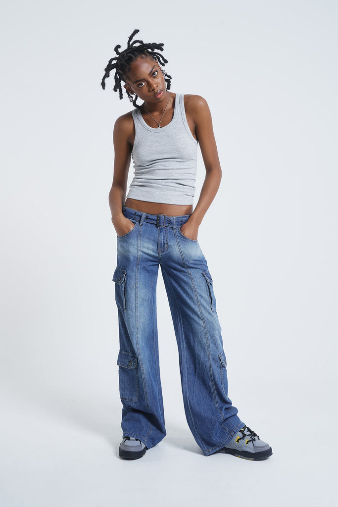 Female model wearing blue washed chambray denim skater fit jeans with belt detail. 