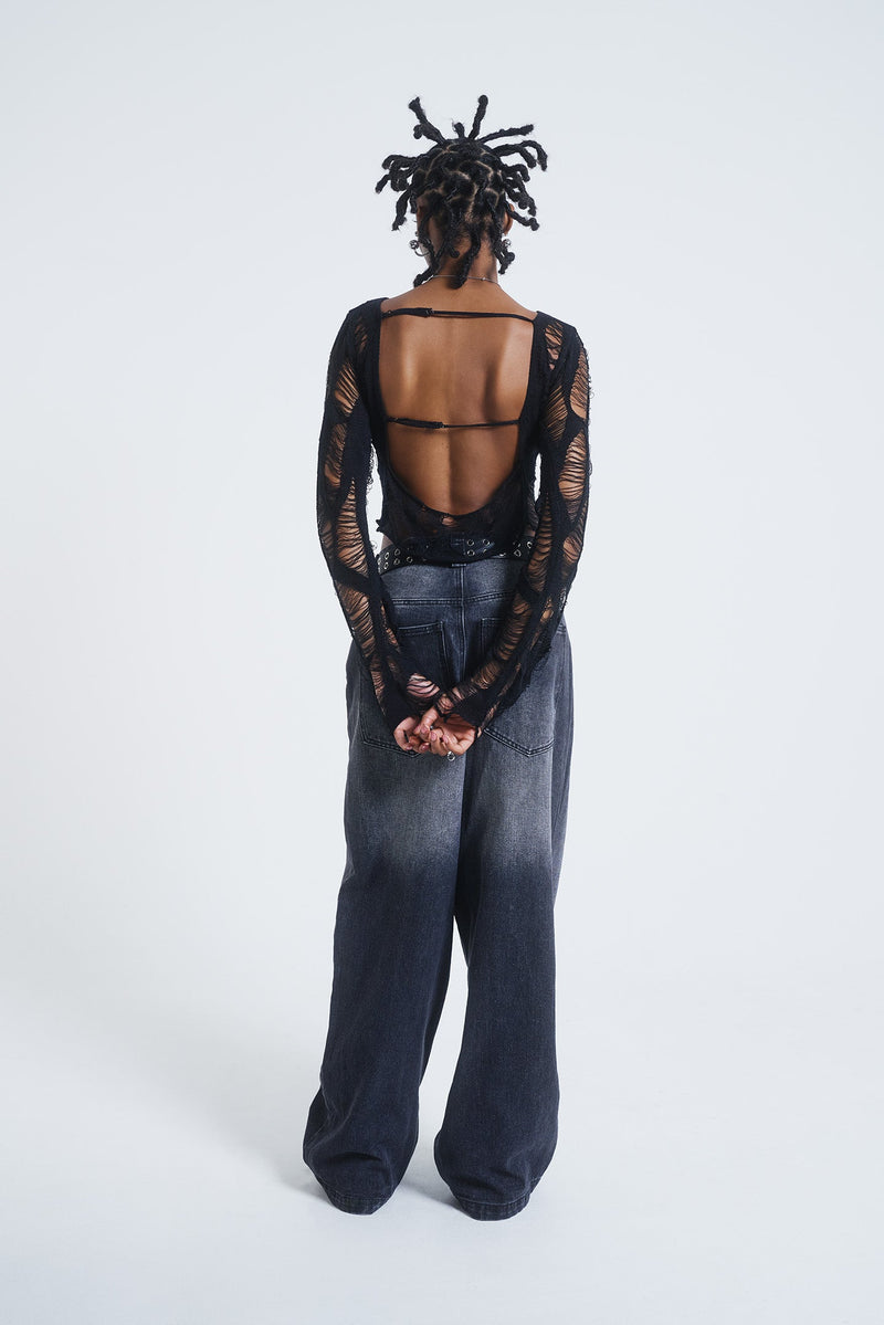 Female model wearing black laddered knitted backless long sleeve top. 