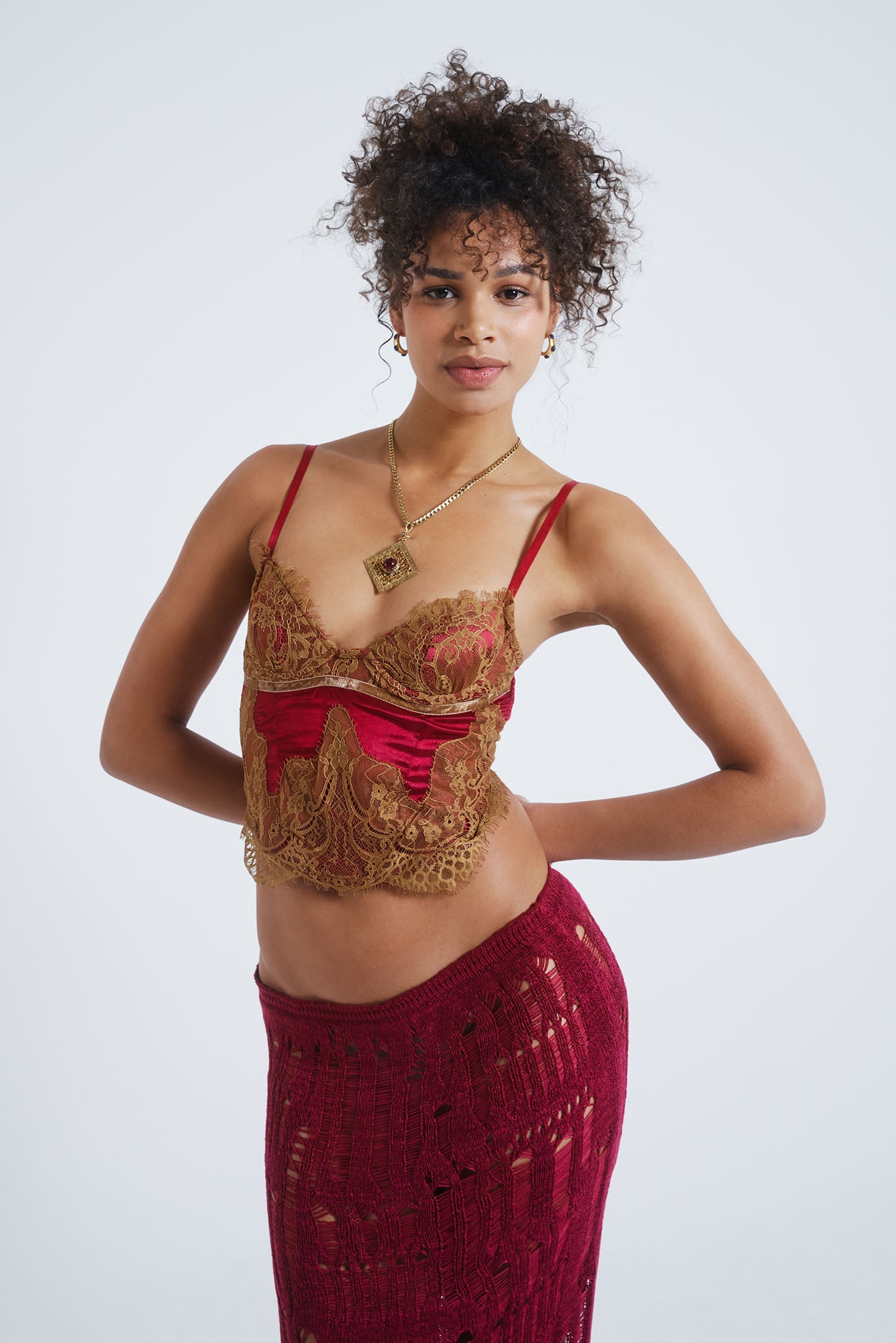 Female model wearing a red satin and mesh corset top with lace detail.  