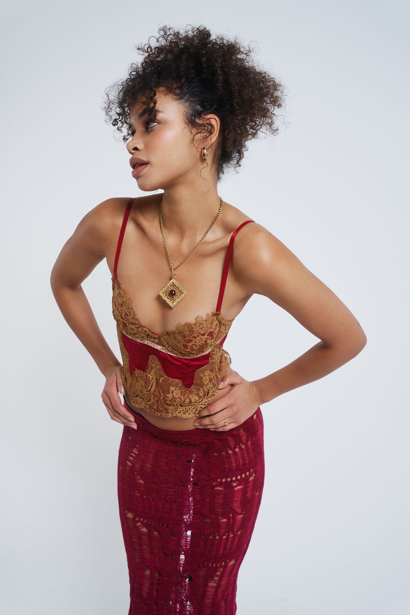 Female model wearing a red satin and mesh corset top with lace detail.  